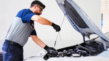 Mecânico verifica o nível de óleo do motor de um carro durante um check-up.