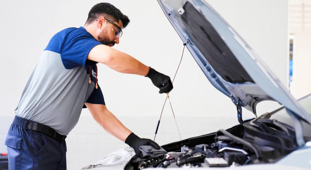 Mecânico verifica o nível de óleo do motor de um carro durante um check-up.