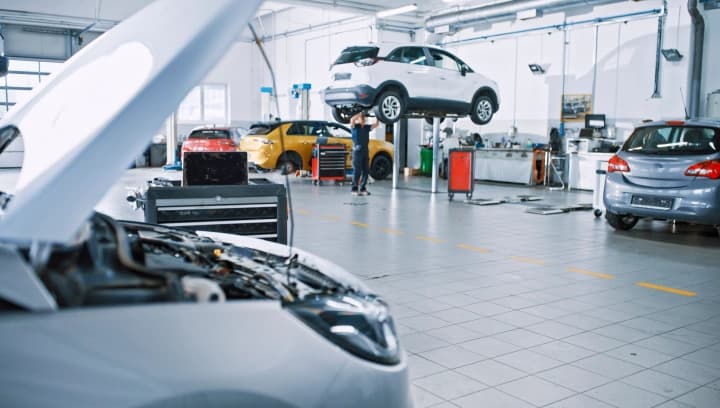 Interior de uma oficina mecânica ampla e bem iluminada com veículos sendo reparados.
